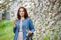 Portrait of a beautiful brunette women in blue jacket  in blossom apple tree garden in spring time. Enjoy Nature. Healthy  smiling Royalty Free Stock Photo