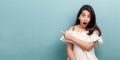 Portrait of beautiful brunette young girl with long straight hair in white dress standing, pointing at wall empty copyspace Royalty Free Stock Photo