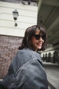 Portrait of beautiful brunette young woman in sunglasses and trendy casual grey jacket walking around city, posing Royalty Free Stock Photo