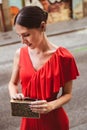 Portrait of beautiful brunette young woman with topknot hairstyle wearing red ruffles dress looking in the purse. Fashion photo Royalty Free Stock Photo