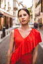 Portrait of beautiful brunette young woman with topknot hairstyle wearing red ruffles dress walking on the street. Fashion photo Royalty Free Stock Photo