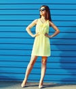 Portrait of beautiful brunette young woman wearing yellow dress on blue background Royalty Free Stock Photo