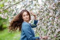 Portrait of a beautiful brunette young women in blue jacket  in blossom apple tree garden in spring time. Enjoy Nature. Healthy Royalty Free Stock Photo