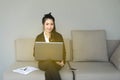 Portrait of beautiful business woman on black suit using a laptop smiling and looking straight while sitting on sofa at home Royalty Free Stock Photo