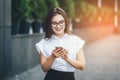 Portrait of a beautiful business woman in a classic financial city street with office buildings holding using a smart Royalty Free Stock Photo