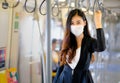Portrait of beautiful business woman with hygiene mask stand with hold handrail in sky train along the way for working during Royalty Free Stock Photo