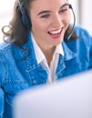 Portrait of beautiful business woman working at her desk with headset and laptop Royalty Free Stock Photo