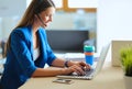 Portrait of beautiful business woman working at her desk with headset and laptop..