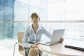 Portrait of beautiful businesswoman with laptop sitting at table in office Royalty Free Stock Photo