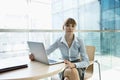 Portrait of beautiful businesswoman with laptop sitting at table in office Royalty Free Stock Photo