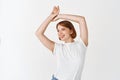 Portrait of beautiful candid girl with natural light make-up, raising hands up and looking aside with carefree smile