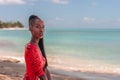 Portrait of Beautiful Caribbean Adult Teen in Barbados. Wearing Red Bikini and Sitting on a tropical beach. Caribbean Sea in Royalty Free Stock Photo