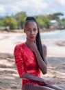 Portrait of Beautiful Caribbean Adult Teen in Barbados. Wearing Red Bikini and Sitting on a tropical beach. Caribbean Sea in Royalty Free Stock Photo