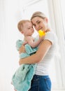 Portrait of beautiful young caring mother holding her baby in blue towel after washing in bath Royalty Free Stock Photo