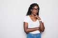 Portrait of beautiful casually dressed young afro american woman in round glasses having doubtful expression, looking away in Royalty Free Stock Photo