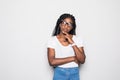 Portrait of beautiful casually dressed young afro american woman in round glasses having doubtful expression, looking away in Royalty Free Stock Photo