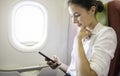Portrait of beautiful caucasian businesswoman female passenger of airplane using networks via smartphone wifi on board.