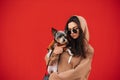 Portrait of a beautiful caucasian female dog-owner wearing sunglasses and a hoodie, hugging her little pet - york terrier in front Royalty Free Stock Photo