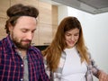 Portrait of a beautiful Caucasian pregnant woman smiling while cooking at home kitchen standing next to her husband Royalty Free Stock Photo