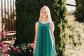 Portrait of beautiful charming attractive blonde girl in green dress  outdoors in a summer sunny park, smiling. Happy positive Royalty Free Stock Photo