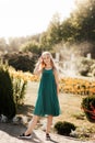 Portrait of beautiful charming attractive blonde girl in green dress  outdoors in a summer sunny park, smiling. Happy positive Royalty Free Stock Photo