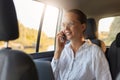 Portrait of beautiful charming cute businesswoman wearing glasses and white shit sitiing in taxi and talking on cell phone and Royalty Free Stock Photo