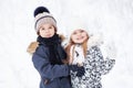 Portrait of beautiful cheerful children on white snow background. Pretty Models wearing winter jackets and hat