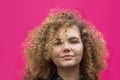 Portrait of beautiful cheerful curly girl on bright pink background. Blonde caucasian woman looking at camera Royalty Free Stock Photo