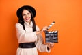 Portrait of beautiful cheerful woman holding clapper action casting time isolated over bright orange color background Royalty Free Stock Photo