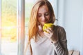 Portrait of beautiful cheerful young smiling red hair woman holding yellow coffee cup, enjoying hot morning coffee at sunrise morn Royalty Free Stock Photo