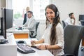 Portrait of beautiful and cheerful young woman telephone operator agent with headset working in office. Royalty Free Stock Photo