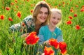 Portrait of beautiful child girl with young mother are wearing casual clothes in field of poppy flowers. Family on Royalty Free Stock Photo