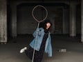 Portrait of a beautiful Chinese woman in blue jeans and black hat hold a toy like lasso and make faces in an abandon factory Royalty Free Stock Photo