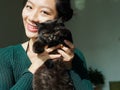 Portrait of beautiful Chinese young girl hug her cute British Shorthair Cat who has amazing orange eyes at home in sunny afternoon