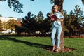 Portrait of a beautiful coed girl listening to music on headphones, outdoors, wearing glasses, holding a book and reading it Royalty Free Stock Photo