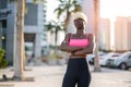 Portrait of blond haired young black woman in sportswear with arms crossed posing on city street at sunset. Royalty Free Stock Photo