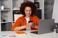 Portrait of a beautiful confident businesswoman using a laptop computer holding a mobile phone sitting in a modern office. Smiling Royalty Free Stock Photo