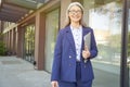 Portrait of a beautiful confident mature business woman wearing classic suit and eyeglasses holding laptop, looking at Royalty Free Stock Photo