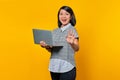 Portrait of beautiful confident young Asian woman holding laptop and pointing at number five with cheerful expression Royalty Free Stock Photo