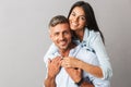 Portrait of beautiful couple man and woman in basic clothing smiling and hugging together, isolated over gray background Royalty Free Stock Photo