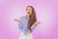 Portrait of a beautiful curly haired girl in a rain of multicolored confetti over an isolated pink background. The girl looks up