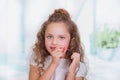 Portrait of beautiful curly little girl painting her nails, wearing a white blouse in a blurred background Royalty Free Stock Photo