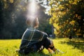 Portrait of a beautiful curly young woman in an autumn park in a hat and a plaid scarf sitting on the grass enjoying nature Royalty Free Stock Photo