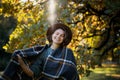 Portrait of a beautiful curly young woman in an autumn park in a hat and a plaid scarf walking enjoying nature Royalty Free Stock Photo