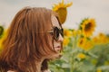 Portrait of a beautiful, cute, sexy red-haired girl in a white dress and glasses. Walks in the sunflowers. Emotion of pleasure, Royalty Free Stock Photo