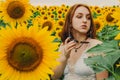 Portrait of a beautiful, cute, sexy red-haired girl in a white dress and glasses. Walks in the sunflowers. Emotion of pleasure, Royalty Free Stock Photo