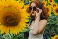 Portrait of a beautiful, cute, sexy red-haired girl in a white dress and glasses. Walks in the sunflowers. Emotion of pleasure, Royalty Free Stock Photo