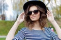 Portrait of a beautiful cute young smiling girl in a black hat and sunglasses in an urban style Royalty Free Stock Photo