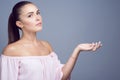 Portrait of beautiful dark-haired girl with perfect skin and nude make up showing empty palm proposing a product