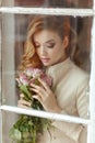 Portrait of a beautiful delicate sensual blonde girl with roses, standing outside the window. Close-up with closed eyes Royalty Free Stock Photo